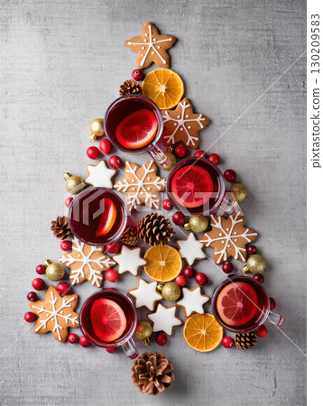 Christmas tree shape made of cookies, mulled wine, orange slices, and decorations arranged flat lay on gray background 130209583