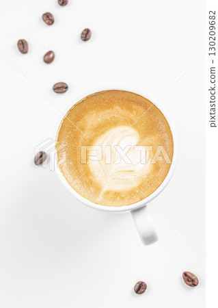 Cup of cappuccino with heart shaped latte art and scattered coffee beans on white background 130209682