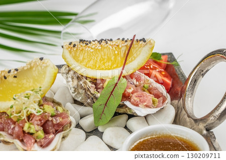 Close up of fresh tuna tartare with lemon, sprouts, and sauce served in oyster shell 130209711