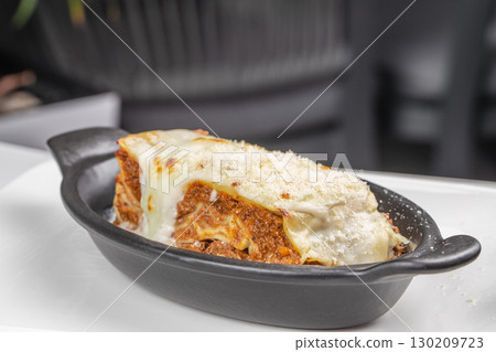 Baked lasagna with melted cheese and meat sauce served in a black ceramic dish Baked lasagna with melted cheese and meat sauce served in a black ceramic dish 130209723