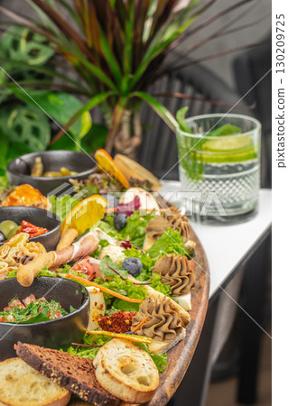 Assorted antipasto platter with meats, cheeses, vegetables, and bread served with cocktail 130209725