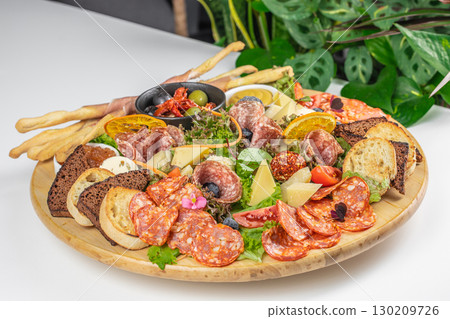 Charcuterie platter with assorted meats, cheeses, bread, and vegetables on a wooden board Charcuterie platter with assorted meats, cheeses, bread, and vegetables on a wooden board 130209726