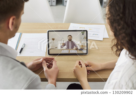 Business people sitting in office having online video call with male colleague using tablet. Business people sitting in office having online video call with male colleague using tablet. 130209902