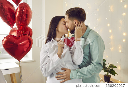 Portrait of young brunette man and woman hugging and kissing at home. Couple in love 130209917