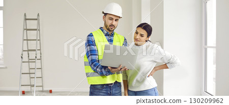 Foreman showing to a young woman design project of apartment renovation on a laptop Foreman showing to a young woman design project of apartment renovation on a laptop 130209962