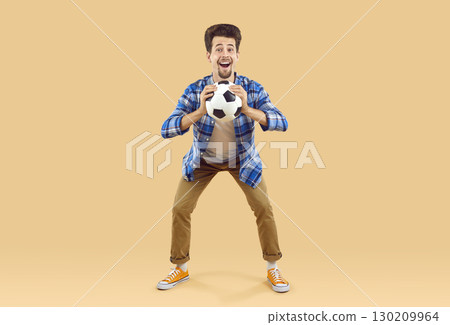 Joyful exited guy in casual blue plaid shirt caught soccer ball Joyful exited guy in casual blue plaid shirt caught soccer ball 130209964