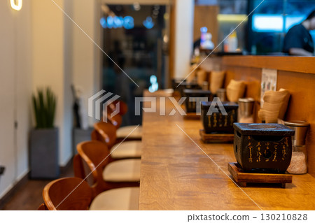 Counterbar seating inside the restaurant with gyukatsu grill tabletop. It is a small portable ceramic or volcanic stone grill. Counterbar seating inside the restaurant with gyukatsu grill tabletop. It is a small portable ceramic or volcanic stone grill. 130210828