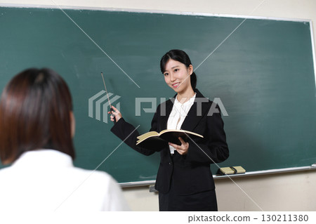 Asian female teacher teaching in front of the blackboard 130211380