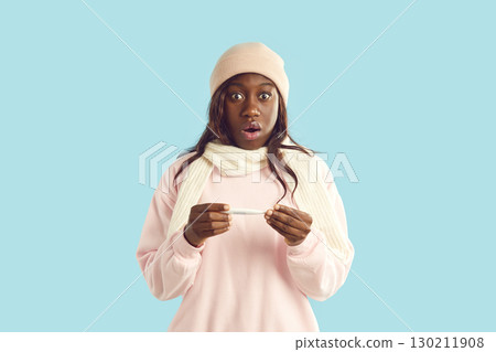 Young surprised shocked woman taking temperature standing isolated on blue studio background. Young surprised shocked woman taking temperature standing isolated on blue studio background. 130211908