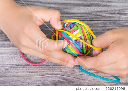 Preschooler hands playing with rubber bands or erasers 130213096