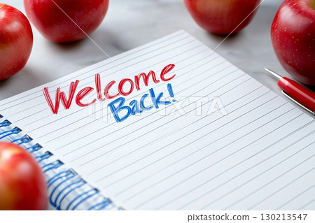 Handwritten Welcome Back on a lined notebook with red and blue ink, surrounded by red apples 130213547