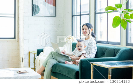 A woman looking at a computer while watching her baby A woman looking at a computer while watching her baby 130214123