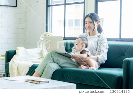 A woman looking at a computer while watching her baby 130214125