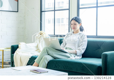 Young woman using a computer in the living room Young woman using a computer in the living room 130214128