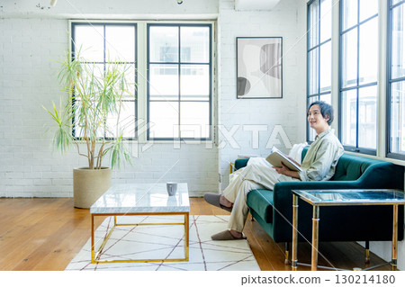 A man sitting on a sofa and reading a book 130214180
