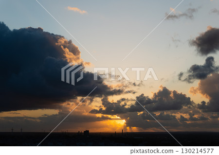 Dramatic sunset with vibrant clouds and golden light illuminating the horizon at dusk Dramatic sunset with vibrant clouds and golden light illuminating the horizon at dusk 130214577