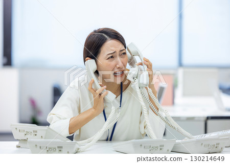 Office woman having trouble answering the phone 130214649