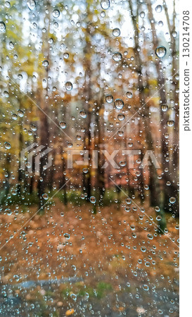 Raindrops on glass surface with blurred autumn forest background 130214708