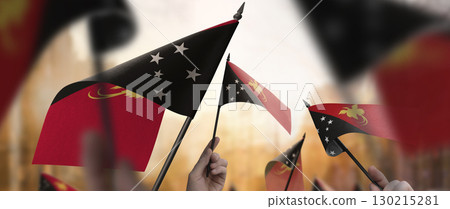 Papua New Guinea flags in their hands on a blurred urban background Papua New Guinea flags in their hands on a blurred urban background 130215281