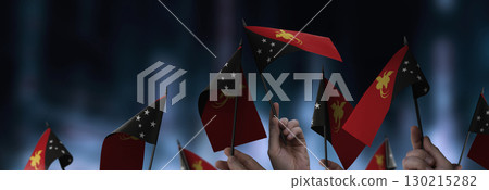Papua New Guinea flags in their hands on a blurred urban background Papua New Guinea flags in their hands on a blurred urban background 130215282