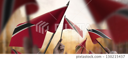 Trinidad and Tobago flags in their hands on a blurred urban background Trinidad and Tobago flags in their hands on a blurred urban background 130215437
