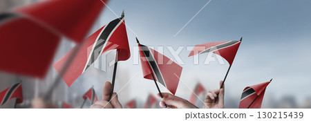 Trinidad and Tobago flags in their hands on a blurred urban background 130215439