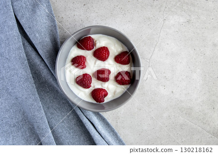 Natural fresh greek yogurt with red raspberry berries in the grey plate and napkin for healthy breakfast. Natural fresh greek yogurt with red raspberry berries in the grey plate and napkin for healthy breakfast. 130218162