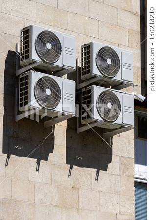 Four air conditioners are mounted on the wall. air conditioners are white. 130218210