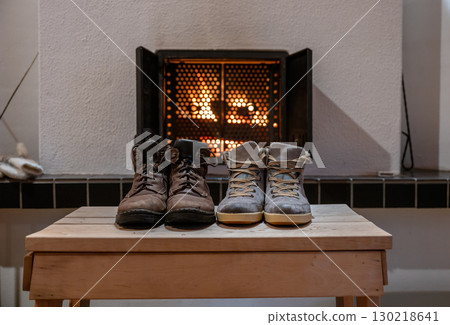 Pair of winter boots drying in front of fireplace indoors cozy home atmosphere Pair of winter boots drying in front of fireplace indoors cozy home atmosphere 130218641