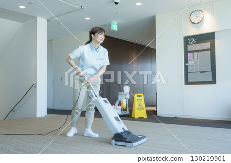 A young female cleaner vacuums the floor of an office building. Photo courtesy of Tokyo Electronics College, Denpa Gakuen Corporation 130219901