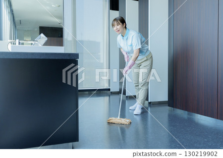 A young female cleaner vacuums the floor of an office building. Photo courtesy of Tokyo Electronics College, Denpa Gakuen Corporation 130219902