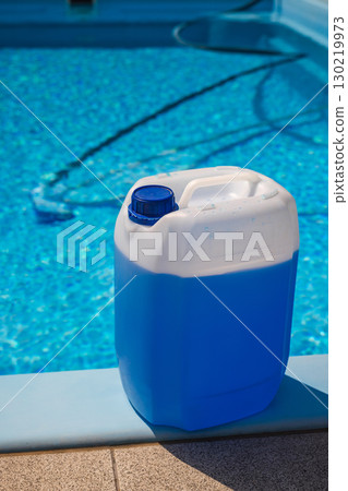 Blue chemical container with a screw cap standing on poolside edge, used for disinfecting and maintaining the clarity of swimming pool water in summer. Blue chemical container with a screw cap standing on poolside edge, used for disinfecting and maintaining the clarity of swimming pool water in summer. 130219973