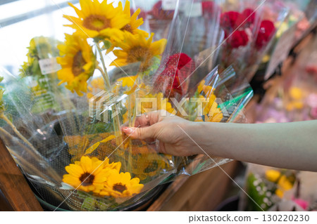 Woman's hands choosing cut flowers 130220230