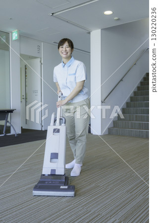 Portrait of a female cleaner vacuuming in an office building. Photo courtesy of Tokyo Electronics College, Denpa Gakuen School Corporation. 130220236