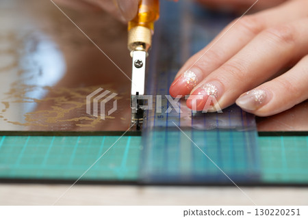 Woman's hand using a glass cutter Woman's hand using a glass cutter 130220251