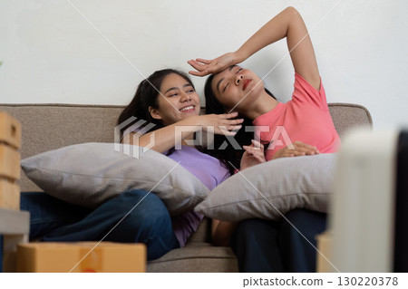Loving LGBTQ couple relaxing on the couch with pillows after moving into their new home 130220378