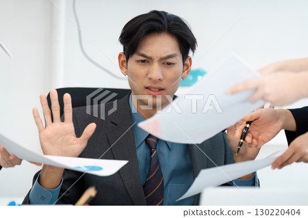Overwhelmed businessman rejecting excessive paperwork in a busy office. Overwhelmed businessman rejecting excessive paperwork in a busy office. 130220404