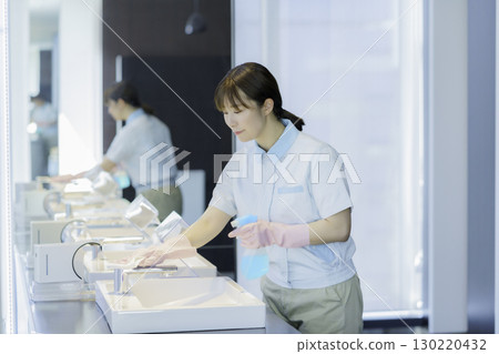 A young female cleaner wipes the sink in an office building bathroom. Photo courtesy of Tokyo Electronics College, Denpa Gakuen Corporation 130220432