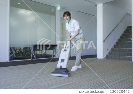 一名年輕的女清潔工正在吸塵辦公大樓的地板。照片提供：東京電子專門學校、電波學園 130220441