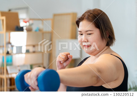 Wellness journey: plus-size woman lifting dumbbells for fitness and strength. 130220512