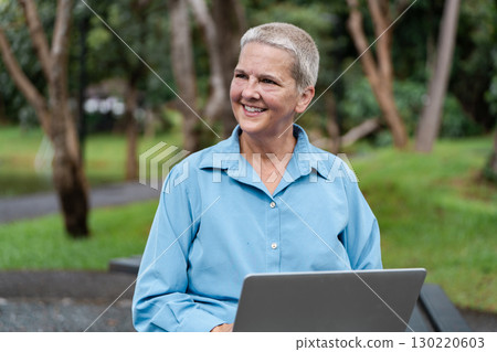Content senior woman enjoying her work while smiling at the park 130220603
