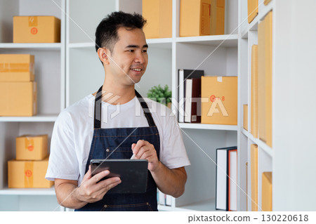 Entrepreneur smiling while managing inventory on tablet in small business startup for online selling 130220618