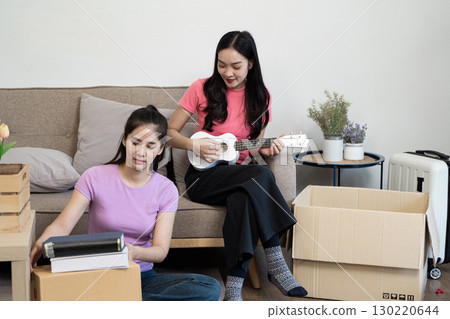 Musical moments A lesbian couple enjoying a ukulele in their new home 130220644