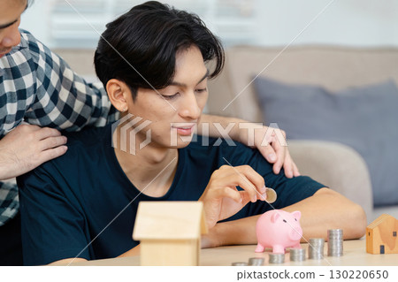 Couple saving money together for real estate investment with a piggy bank 130220650