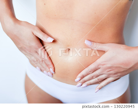 Close up of female caucasian young adult in white underwear touching flat stomach 130220945