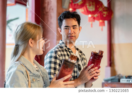 Couple sharing a moment with traditional incense sticks in a cultural setting Couple sharing a moment with traditional incense sticks in a cultural setting 130221085