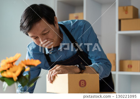 Elderly man packing boxes in a modern workspace with flowers 130221095