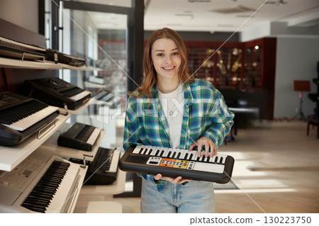 A smiling musician holding a keyboard instrument in a professional studio setting 130223750