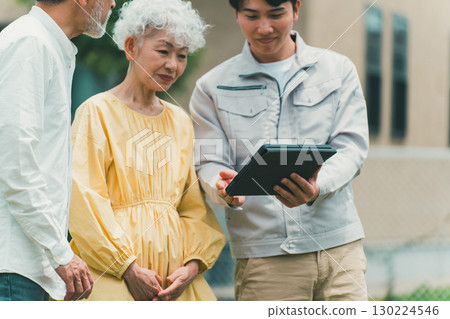 A contractor explaining to a senior couple using a tablet 130224546