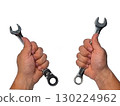 Two hands holding different types of wrenches.  130224962